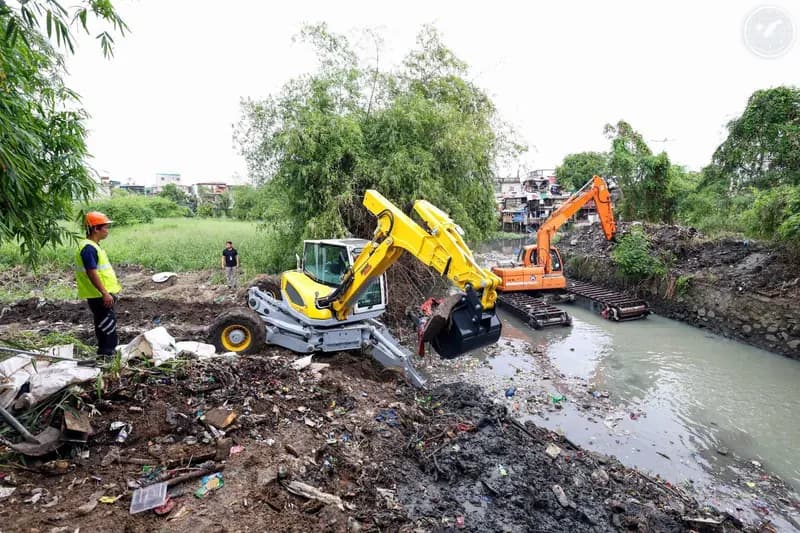 An amphibious excavator clearing a creek bank